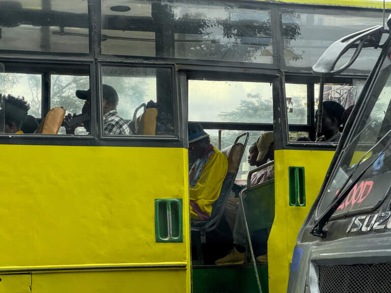 Driving through downtown Nairobi, a yellow matatu or minibus with open door